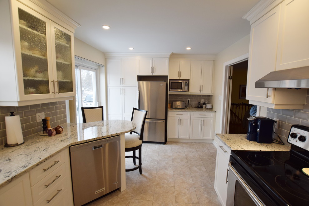 Example of a mid-sized transitional u-shaped ceramic tile enclosed kitchen design in Ottawa with an undermount sink, shaker cabinets, white cabinets, granite countertops, gray backsplash, glass tile backsplash, stainless steel appliances and a peninsula