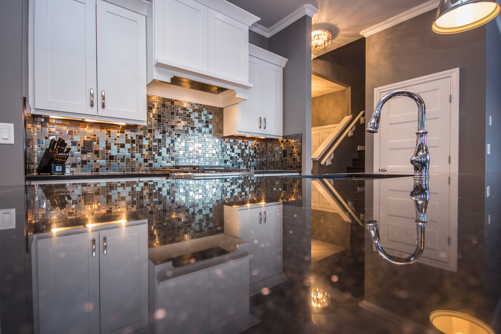 Example of a mid-sized transitional l-shaped porcelain tile eat-in kitchen design in Calgary with a double-bowl sink, shaker cabinets, white cabinets, multicolored backsplash, mosaic tile backsplash, stainless steel appliances, an island and quartz countertops