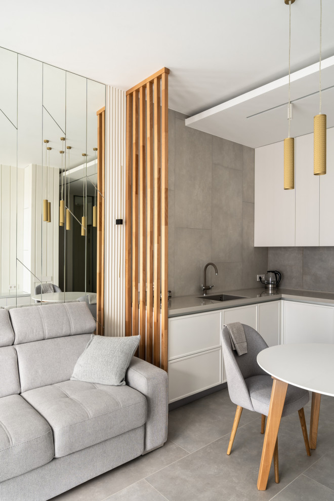 Esempio di una sala da pranzo aperta verso il soggiorno design di medie dimensioni con pareti bianche, pavimento in gres porcellanato, pavimento grigio, soffitto ribassato e pannellatura