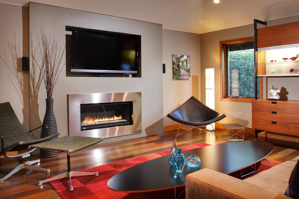 This is an example of a mid-sized contemporary formal enclosed living room in Sacramento with a ribbon fireplace, a wall-mounted tv, white walls, medium hardwood floors and a metal fireplace surround.