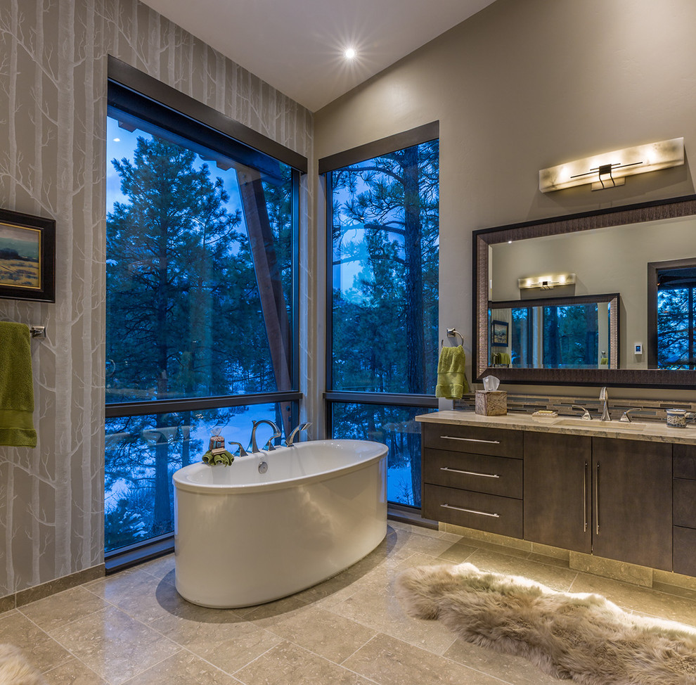 This is an example of a large contemporary master bathroom in Albuquerque with flat-panel cabinets, grey cabinets, a freestanding tub, an open shower, beige tile, glass tile, beige walls, travertine floors, an undermount sink and granite benchtops.