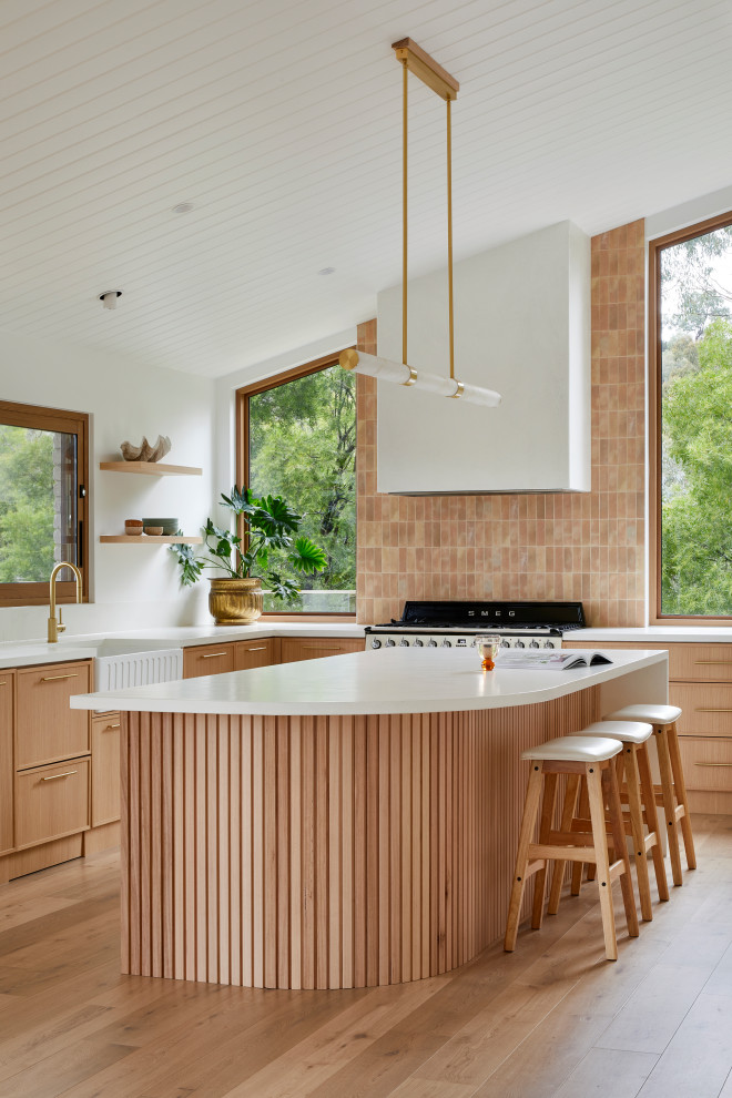 Idéer för att renovera ett stort funkis vit vitt u-kök, med en rustik diskho, skåp i shakerstil, skåp i mellenmörkt trä, rosa stänkskydd, stänkskydd i porslinskakel, svarta vitvaror, mellanmörkt trägolv, en köksö och brunt golv