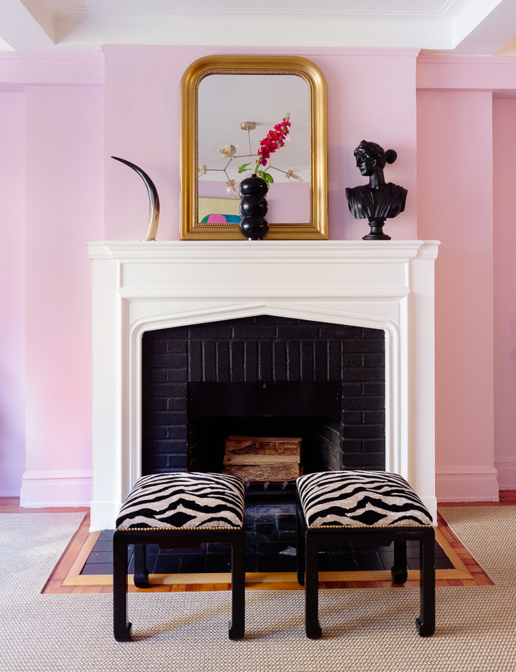 This is an example of a mid-sized eclectic enclosed living room in New York with pink walls, medium hardwood floors, a standard fireplace, a brick fireplace surround, no tv and brown floor.