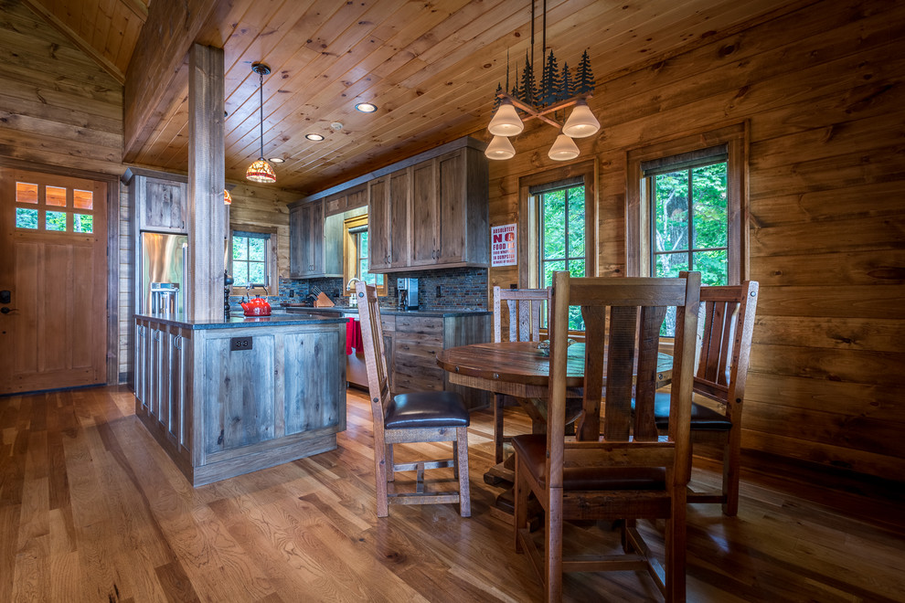 Eat-in kitchen - mid-sized rustic l-shaped medium tone wood floor and brown floor eat-in kitchen idea in Charlotte with an undermount sink, shaker cabinets, dark wood cabinets, granite countertops, multicolored backsplash, glass tile backsplash, stainless steel appliances and an island