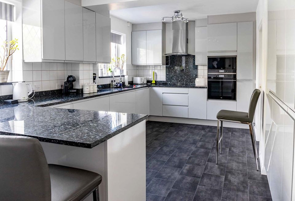 Inspiration for a modern l-shaped kitchen in West Midlands with an undermount sink, white cabinets, granite benchtops, blue splashback, panelled appliances, a peninsula and blue benchtop.