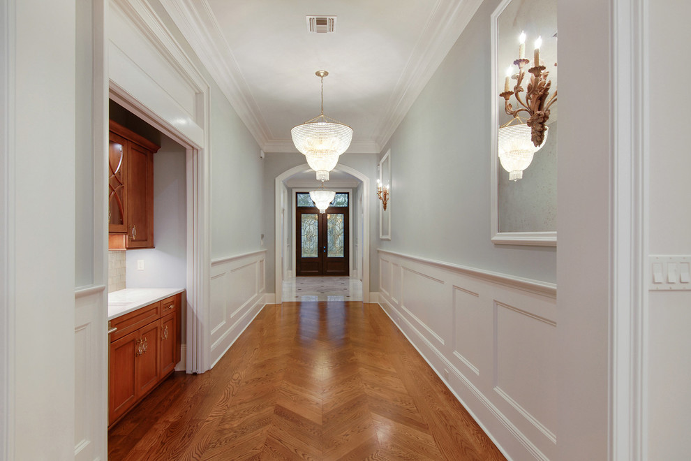 This is an example of a large traditional entry hall in New Orleans with blue walls, medium hardwood floors, a double front door and a glass front door.