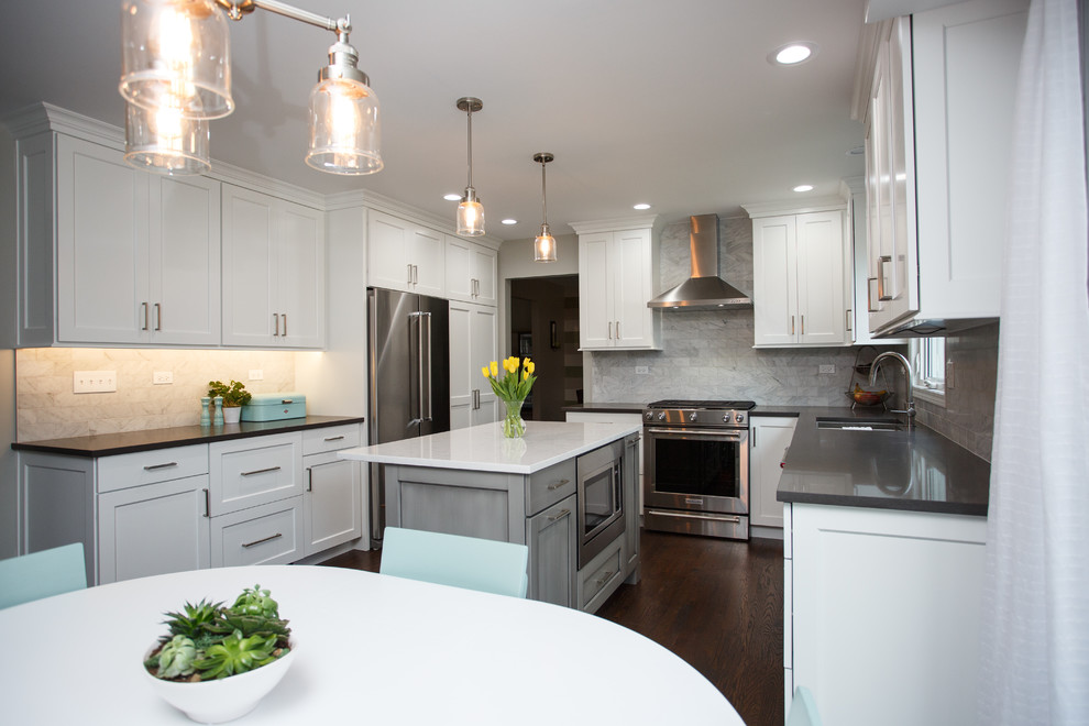This is an example of a mid-sized transitional kitchen in Chicago with an undermount sink, recessed-panel cabinets, white cabinets, quartz benchtops, grey splashback, marble splashback, stainless steel appliances, dark hardwood floors, with island and white benchtop.