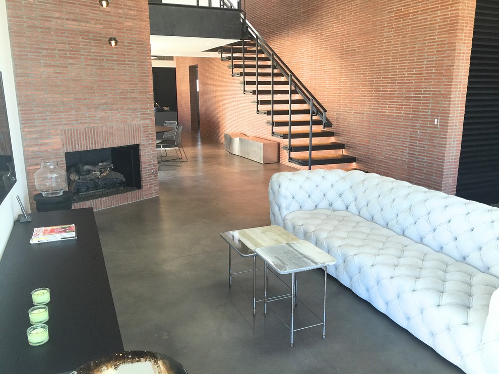 Design ideas for a large industrial formal loft-style living room in Los Angeles with red walls, concrete floors, a standard fireplace, a brick fireplace surround and grey floor.