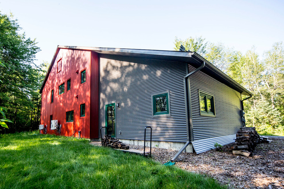 Photo of a large country two-storey red house exterior in Ottawa with metal siding, a gable roof and a metal roof.