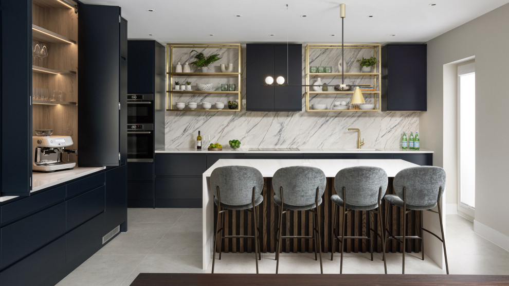 This is an example of a large contemporary l-shaped kitchen in Dublin with an integrated sink, flat-panel cabinets, blue cabinets, quartz worktops, multi-coloured splashback, engineered quartz splashback, integrated appliances, limestone flooring, an island, grey floors and white worktops.