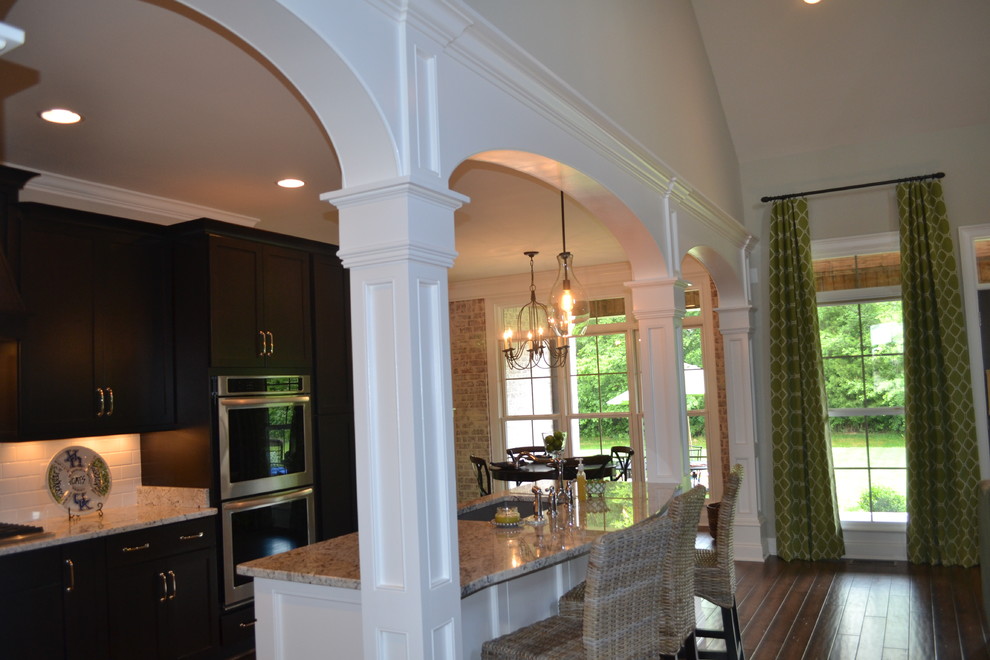 Eat-in kitchen - mid-sized transitional dark wood floor eat-in kitchen idea with raised-panel cabinets, dark wood cabinets, granite countertops, stainless steel appliances and an island