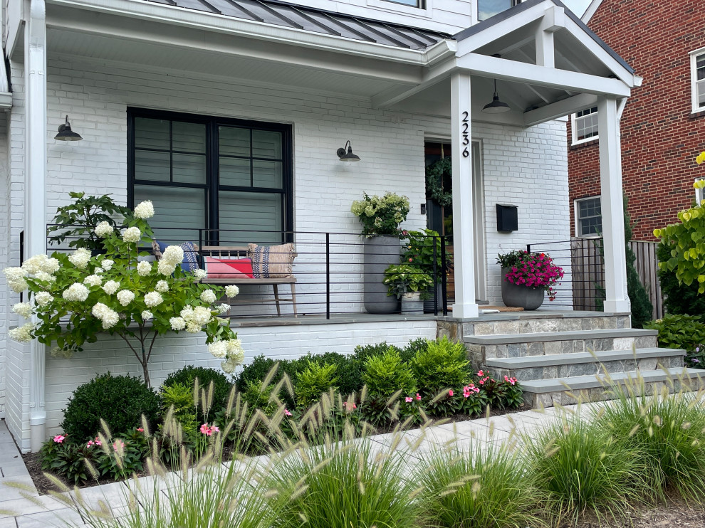 Immagine di un portico minimal davanti casa con un giardino in vaso, pavimentazioni in pietra naturale, un tetto a sbalzo e parapetto in metallo