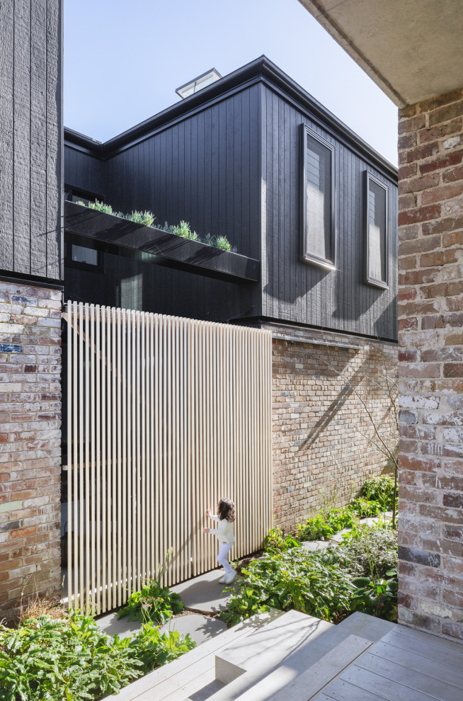 Inspiration for a mid-sized modern two-storey brick black duplex exterior in Sydney with a metal roof.