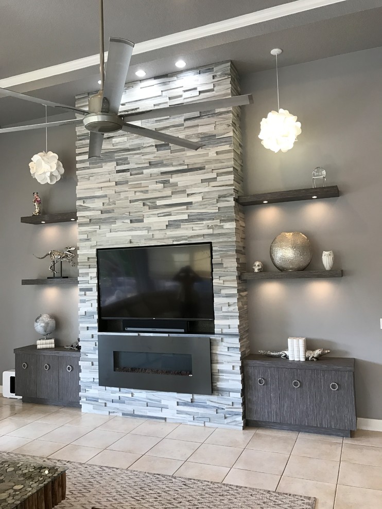 Photo of a large contemporary open concept living room in Miami with grey walls, ceramic floors, a standard fireplace, a stone fireplace surround, a built-in media wall and beige floor.