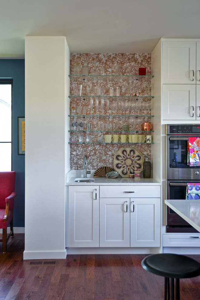 Small transitional l-shaped dark wood floor eat-in kitchen photo in Seattle with an undermount sink, shaker cabinets, white cabinets, quartz countertops, metallic backsplash, stainless steel appliances, an island and white countertops