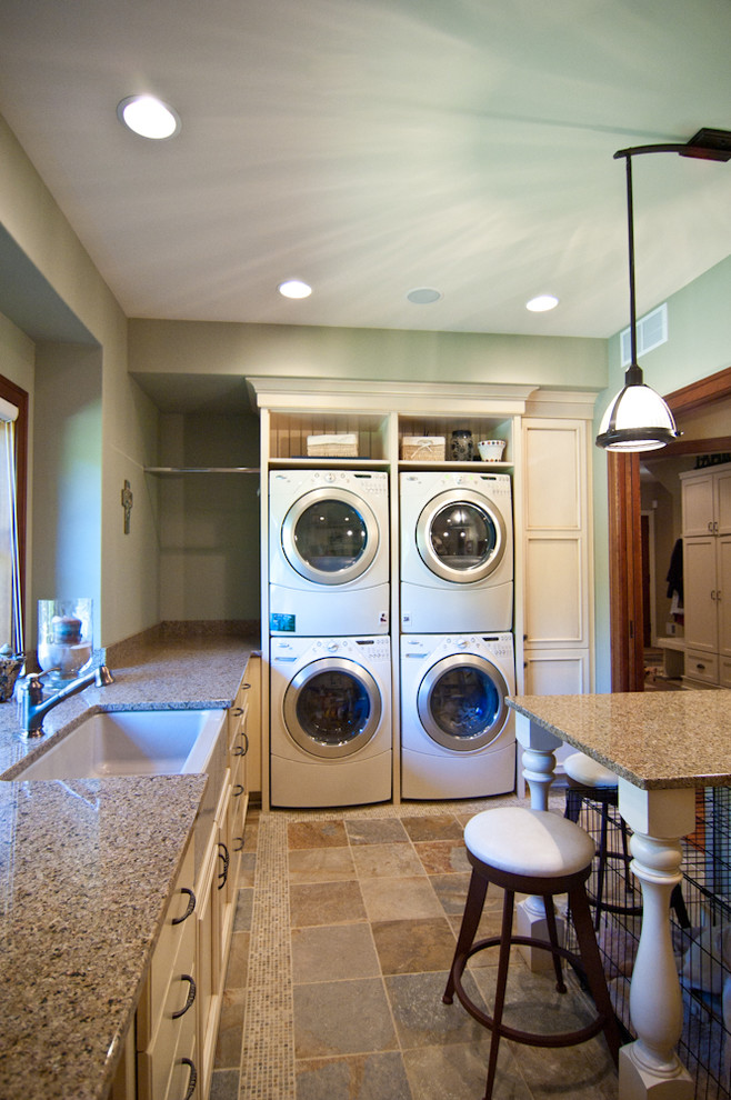 Country laundry room in Grand Rapids with a farmhouse sink, solid surface benchtops and a stacked washer and dryer.