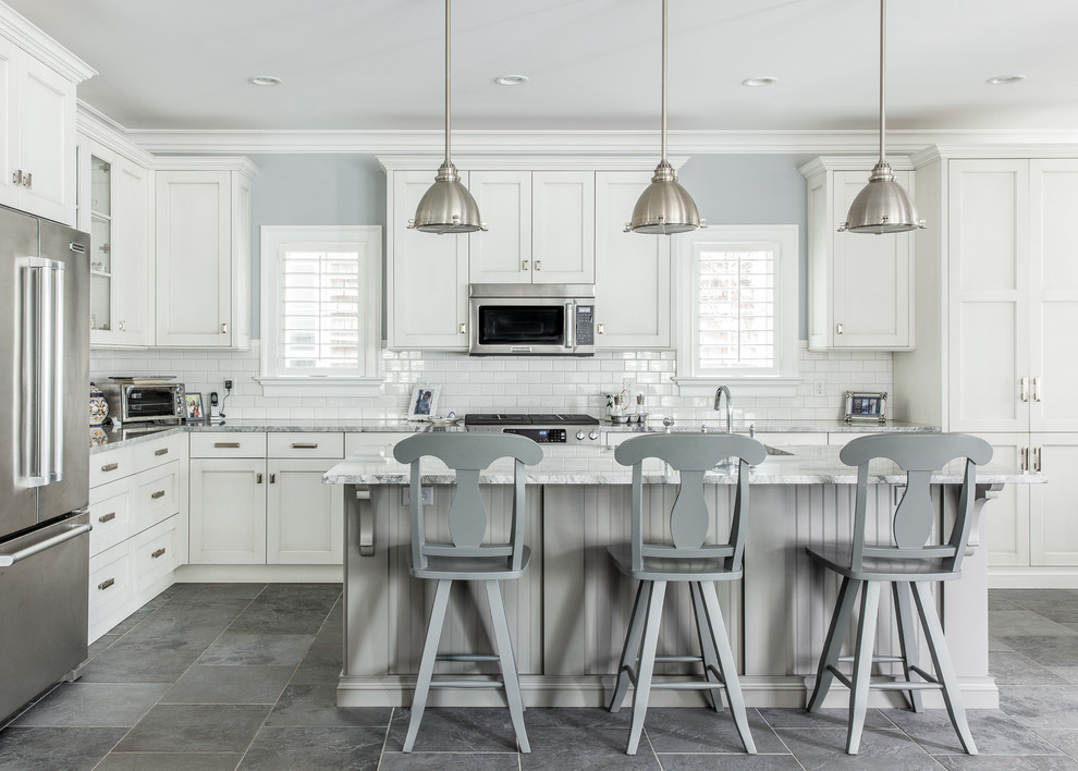 Photo of a large traditional l-shaped kitchen in New York with white cabinets, granite benchtops, white splashback, subway tile splashback, with island, stainless steel appliances, slate floors and recessed-panel cabinets.