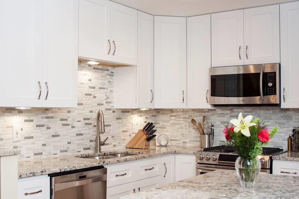 This is an example of a large transitional u-shaped eat-in kitchen in DC Metro with a double-bowl sink, recessed-panel cabinets, white cabinets, granite benchtops, grey splashback, ceramic splashback, stainless steel appliances, light hardwood floors, with island and brown floor.