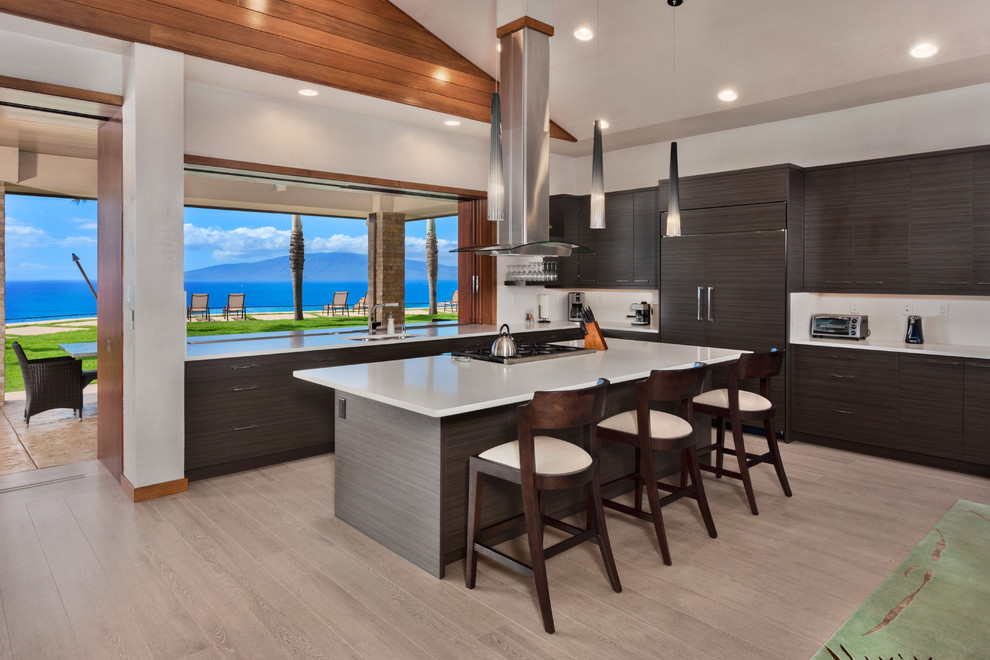 Large contemporary l-shaped open plan kitchen in Hawaii with an undermount sink, flat-panel cabinets, window splashback, panelled appliances, with island, beige floor, dark wood cabinets, porcelain floors and quartz benchtops.