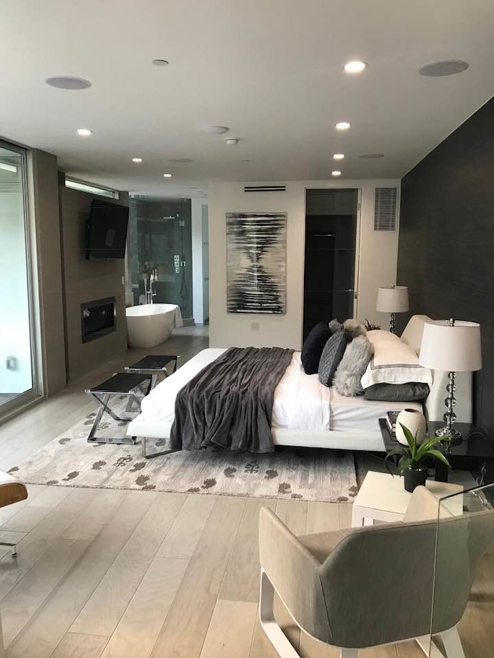 Design ideas for a mid-sized modern master bedroom in Los Angeles with white walls, light hardwood floors, a concrete fireplace surround and beige floor.