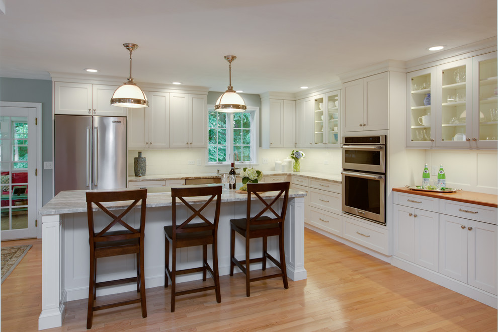 Inspiration for a transitional l-shaped light wood floor eat-in kitchen remodel in Boston with an undermount sink, recessed-panel cabinets, white cabinets, quartzite countertops, white backsplash, subway tile backsplash, stainless steel appliances and an island