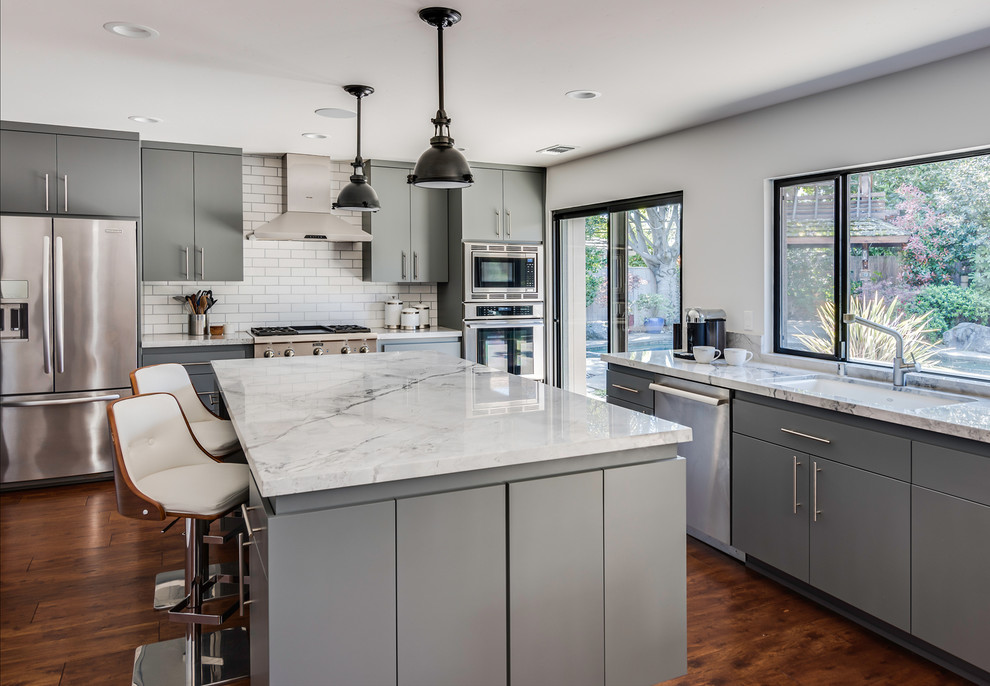 Photo of a transitional l-shaped kitchen in Sacramento with an undermount sink, flat-panel cabinets, grey cabinets, quartzite benchtops, white splashback, subway tile splashback, stainless steel appliances and with island.