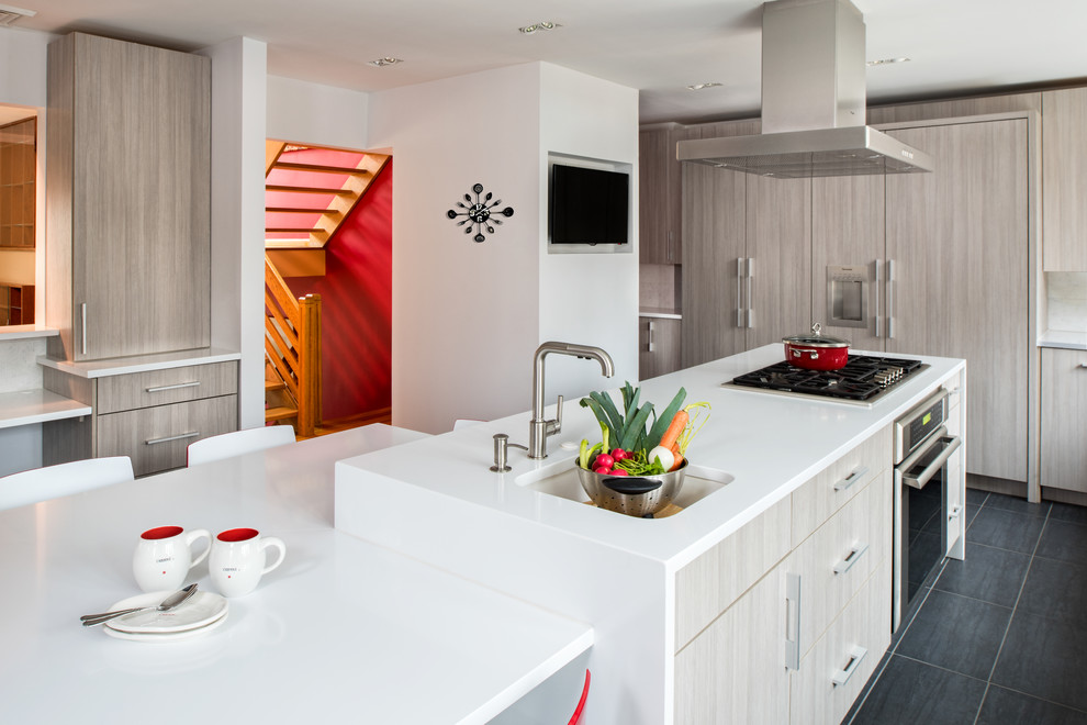This is an example of a contemporary u-shaped eat-in kitchen in New York with an undermount sink, flat-panel cabinets, stainless steel appliances, with island, light wood cabinets, quartz benchtops, porcelain floors and grey floor.
