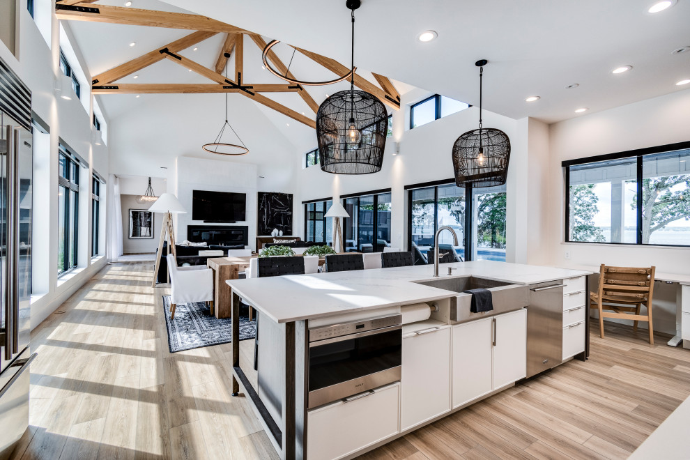 На фото: кухня-столовая среднего размера в стиле модернизм с белыми стенами, полом из ламината, коричневым полом и балками на потолке с
