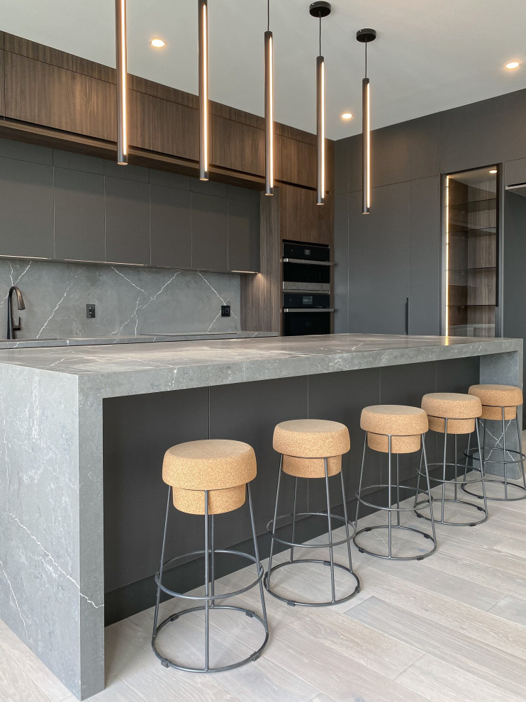 Große Moderne Wohnküche mit flächenbündigen Schrankfronten, Quarzwerkstein-Arbeitsplatte, Küchenrückwand in Grau, Rückwand aus Quarzwerkstein, Kücheninsel, grauer Arbeitsplatte, dunklen Holzschränken und hellem Holzboden in Toronto