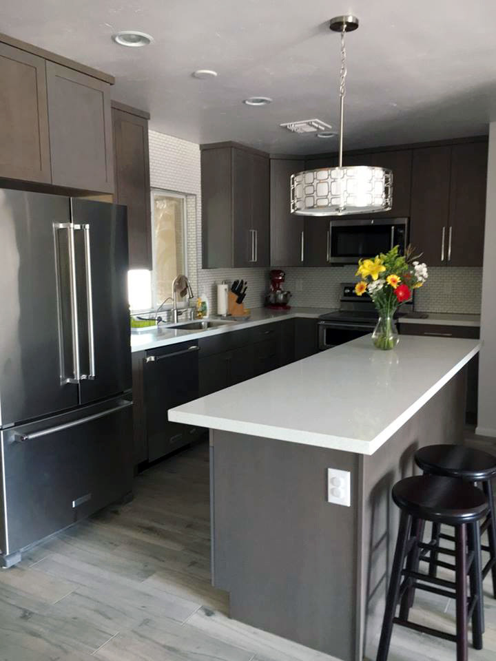 Mid-sized transitional l-shaped medium tone wood floor enclosed kitchen photo in Phoenix with an undermount sink, shaker cabinets, gray cabinets, quartzite countertops, white backsplash, subway tile backsplash, stainless steel appliances and an island