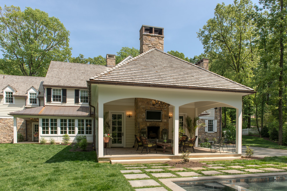 This is an example of a mid-sized traditional backyard patio in Philadelphia with a fire feature and a roof extension.