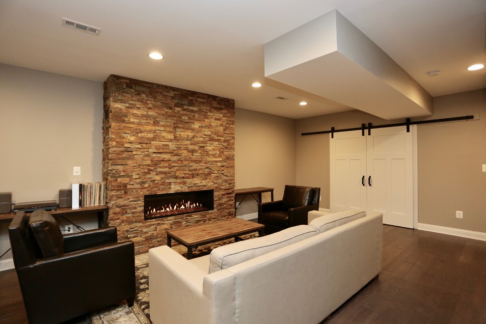 Design ideas for a large contemporary fully buried basement in DC Metro with brown walls, dark hardwood floors, a ribbon fireplace, a stone fireplace surround and brown floor.