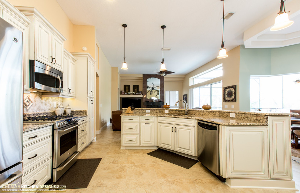 Photo of a large traditional u-shaped open plan kitchen in Orlando with an undermount sink, raised-panel cabinets, white cabinets, granite benchtops, multi-coloured splashback, stone tile splashback, stainless steel appliances, travertine floors and with island.