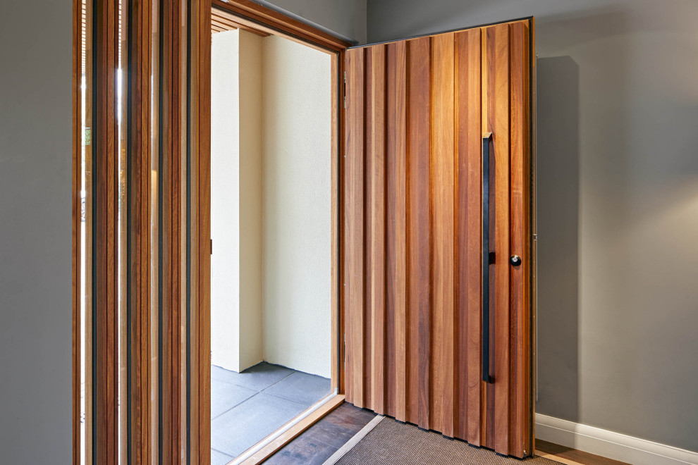 Foto på en entré, med en enkeldörr och mellanmörk trädörr