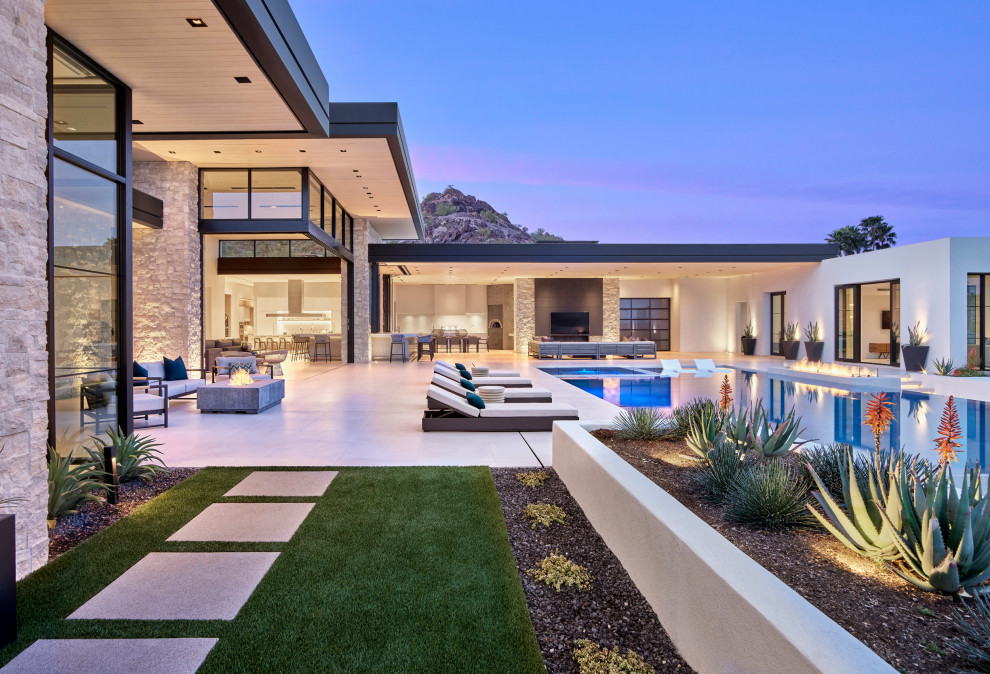 This is an example of an expansive modern backyard custom-shaped infinity pool in Phoenix with a hot tub.