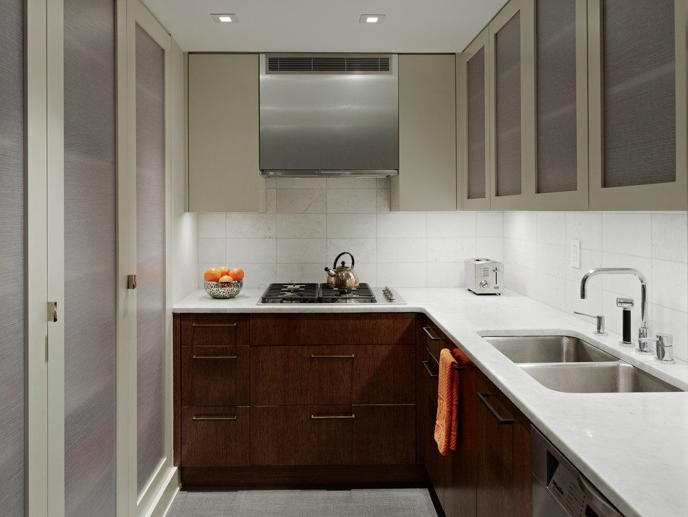 Photo of a mid-sized modern l-shaped separate kitchen in New York with white splashback, a double-bowl sink, flat-panel cabinets, dark wood cabinets, marble benchtops, porcelain splashback, stainless steel appliances, no island and white benchtop.