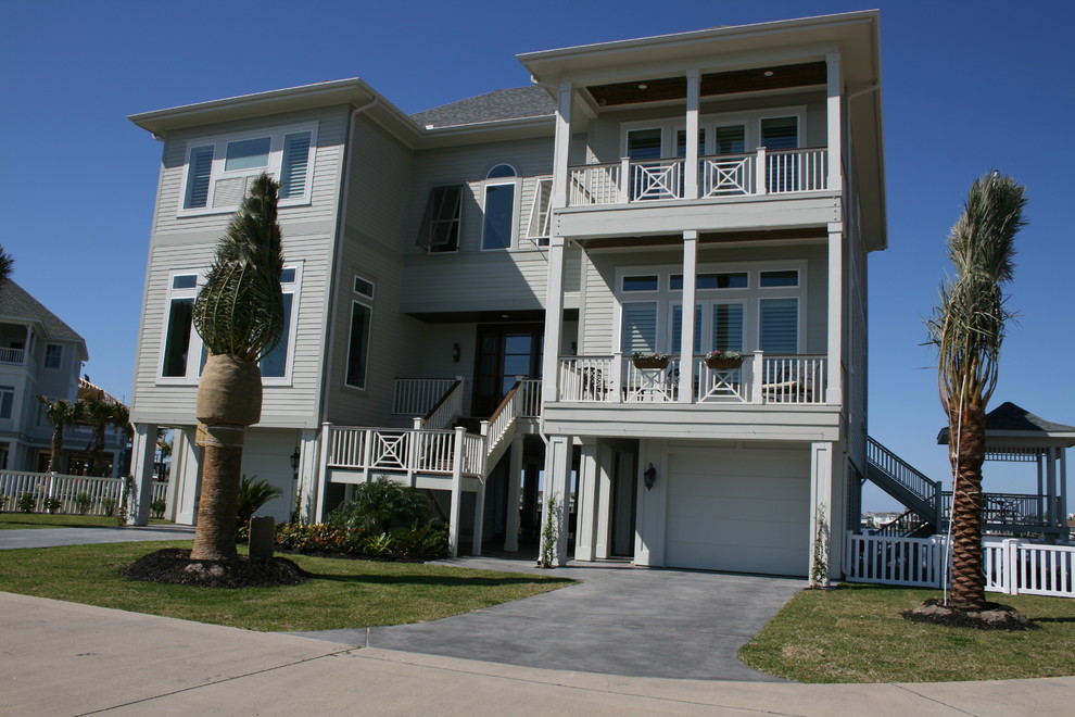 Large beach style three-storey grey house exterior in Houston with concrete fiberboard siding, a hip roof and a shingle roof.
