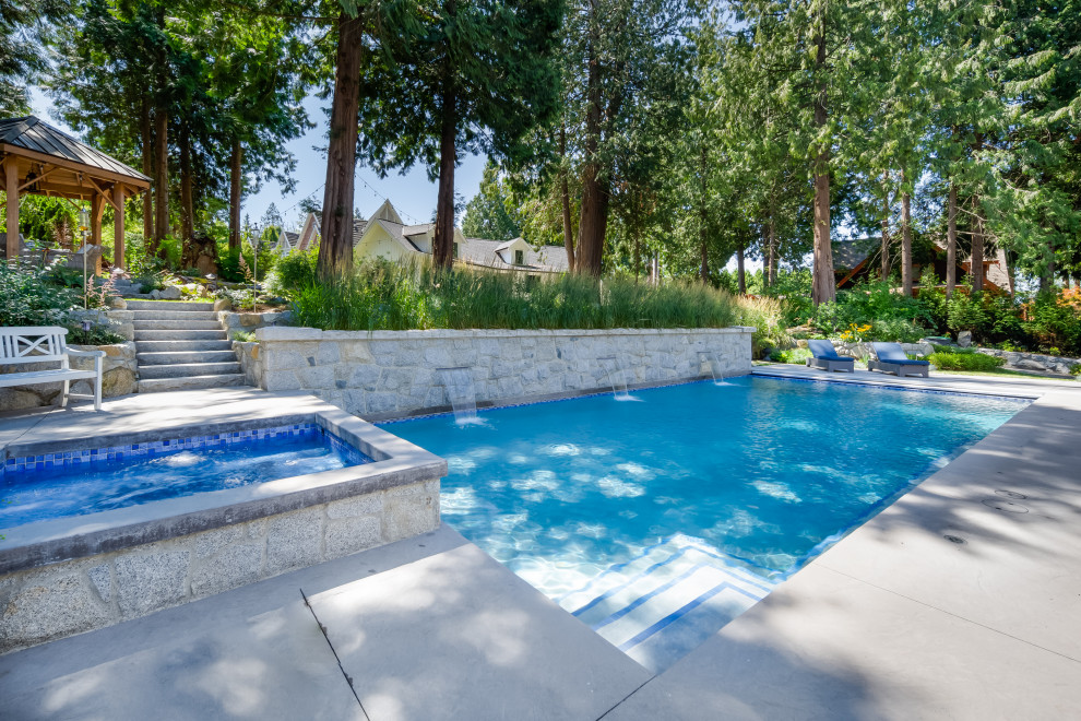 Foto di una piscina stile americano rettangolare dietro casa con una vasca idromassaggio e pavimentazioni in cemento