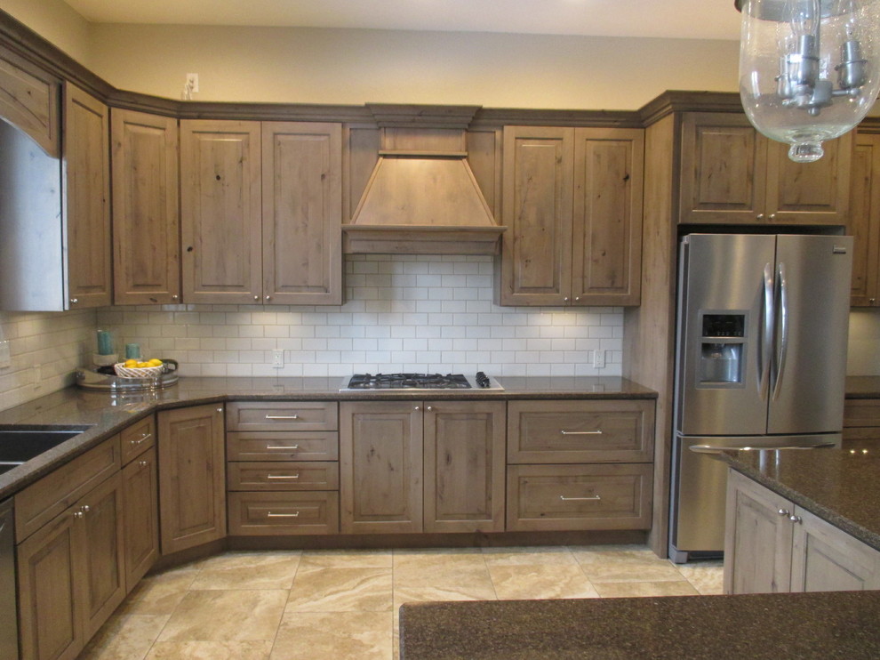 Inspiration for a mid-sized transitional l-shaped ceramic tile open concept kitchen remodel with an undermount sink, raised-panel cabinets, beige backsplash, subway tile backsplash, stainless steel appliances, an island, medium tone wood cabinets and quartz countertops