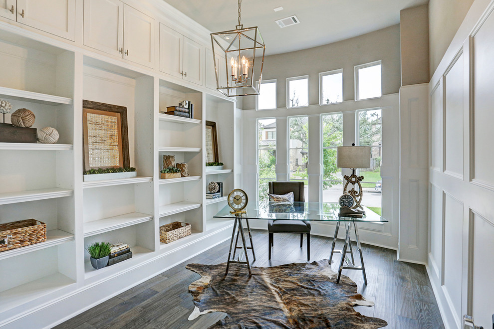 This is an example of a mid-sized beach style study room in Houston with white walls, dark hardwood floors, no fireplace, a freestanding desk and brown floor.