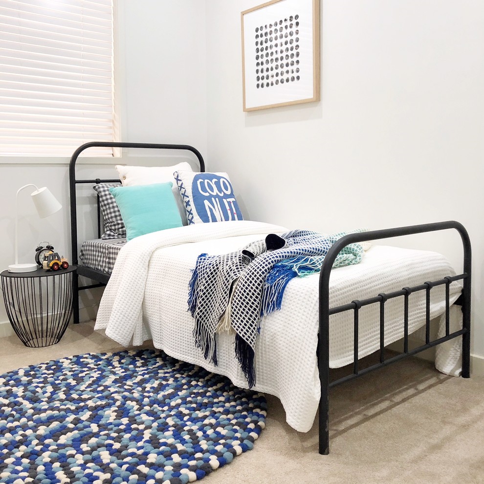 This is an example of a beach style gender-neutral kids' bedroom for kids 4-10 years old in Sydney with white walls, carpet and beige floor.