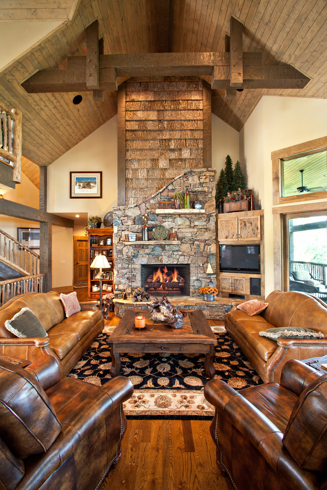 Photo of a large country living room in Other with beige walls, a standard fireplace, a stone fireplace surround and a built-in media wall.