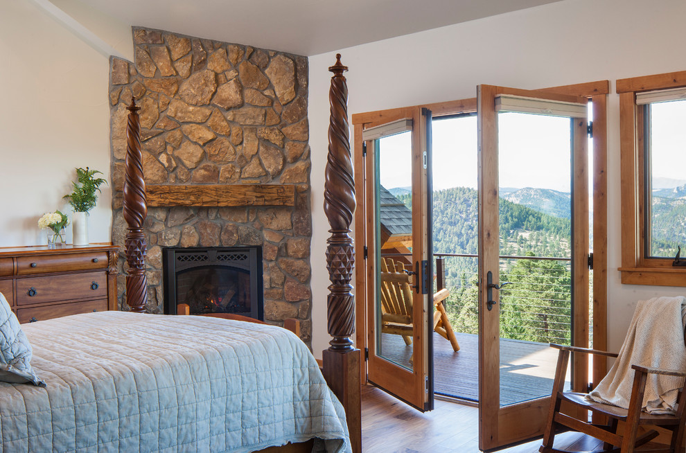 Photo of a country master bedroom in Denver with white walls, a corner fireplace and a stone fireplace surround.