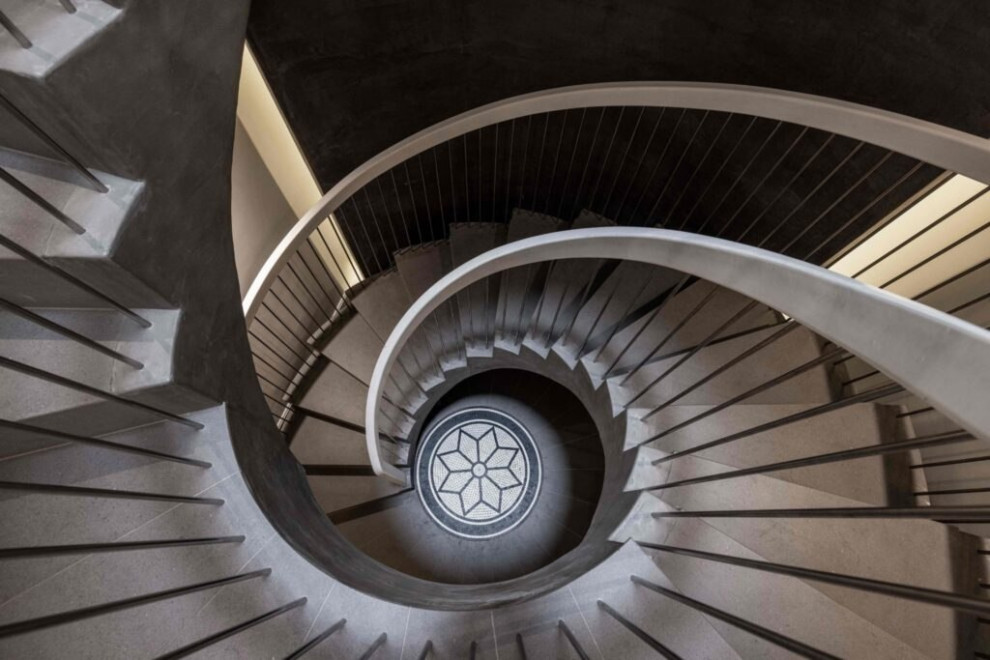 Mid-sized contemporary concrete spiral staircase in London with concrete risers, metal railing and decorative wall panelling.