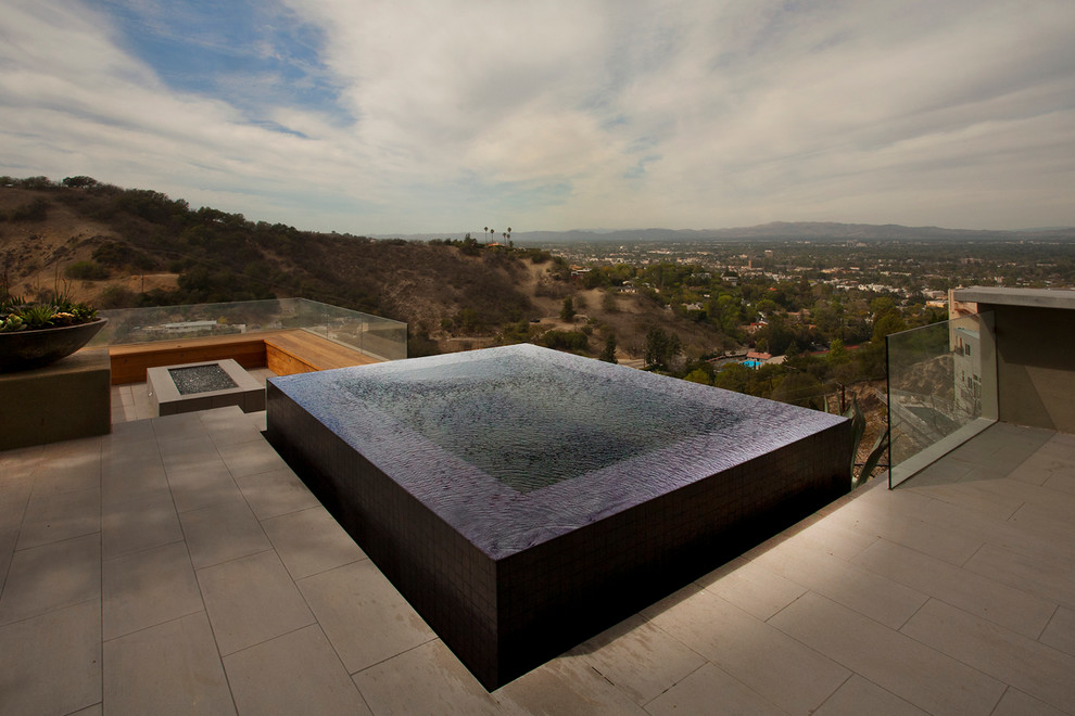 Small modern backyard custom-shaped infinity pool in Los Angeles with a water feature and tile.