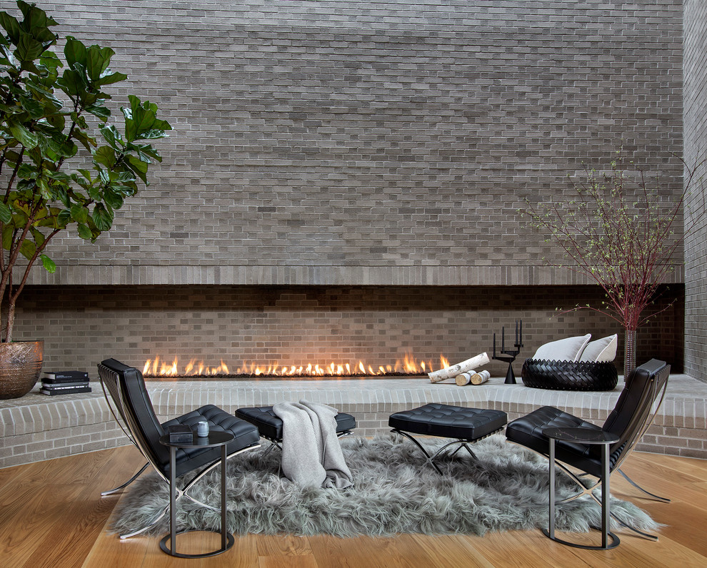 Inspiration for a contemporary family room in Denver with grey walls, medium hardwood floors, a ribbon fireplace, a brick fireplace surround and brown floor.