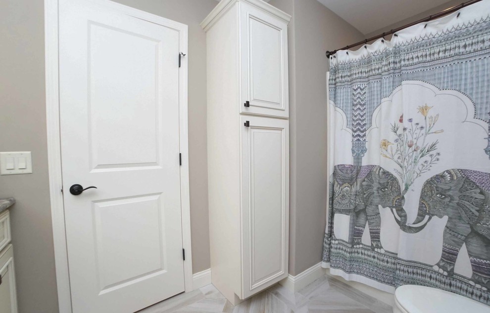 This is an example of a mid-sized transitional bathroom in Chicago with recessed-panel cabinets, white cabinets, an alcove shower, a two-piece toilet, brown walls, porcelain floors, an undermount sink, granite benchtops, brown floor and a shower curtain.