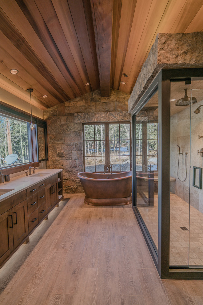 Design ideas for a large contemporary master bathroom in Denver with flat-panel cabinets, medium wood cabinets, a freestanding tub, beige tile, travertine, porcelain floors, an undermount sink, limestone benchtops, a hinged shower door and beige benchtops.