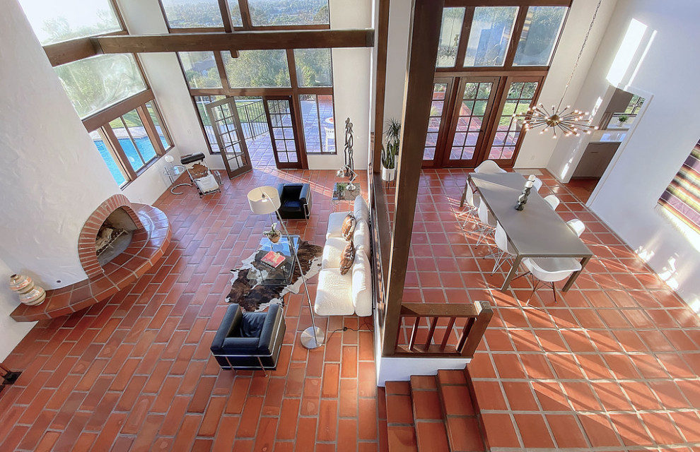 This is an example of a large retro open plan living room in Santa Barbara with white walls, terracotta flooring and a standard fireplace.
