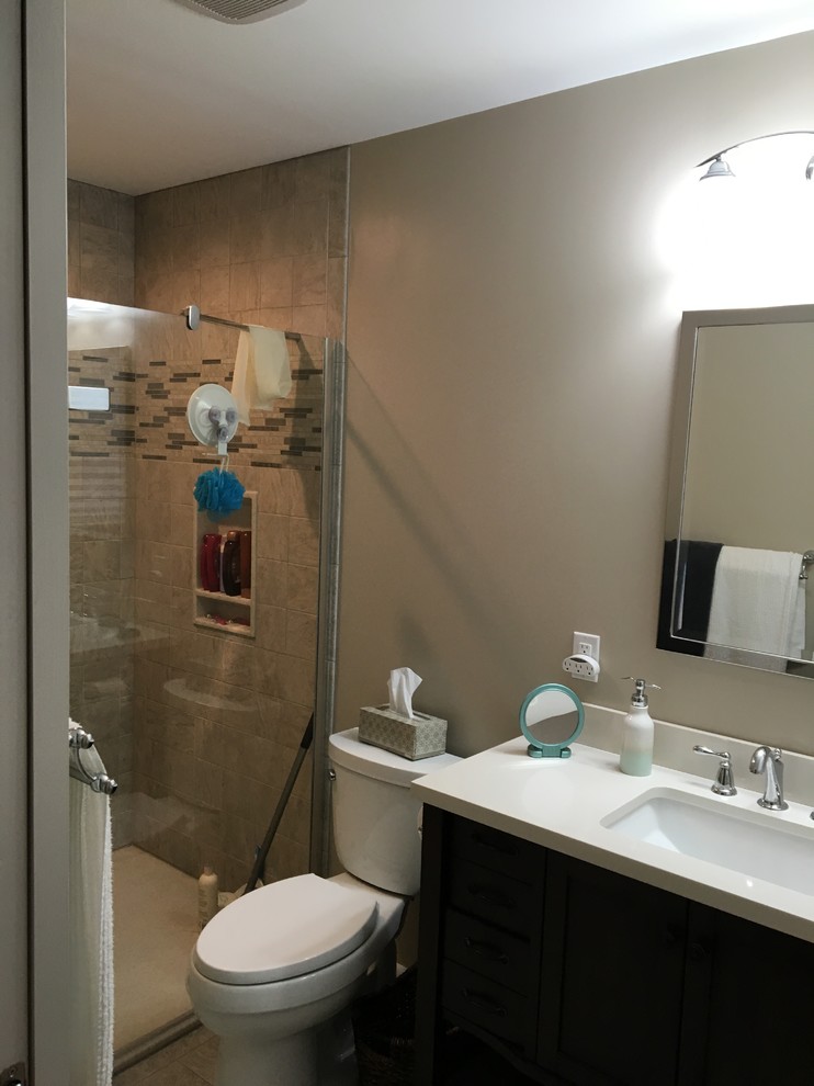 Alcove shower - small transitional 3/4 alcove shower idea in Baltimore with black cabinets, a one-piece toilet, brown walls, an undermount sink, solid surface countertops, a hinged shower door and white countertops